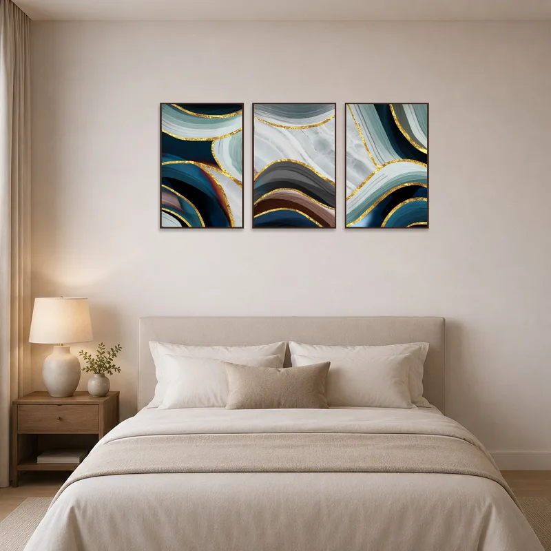 An abstract triptych with touches of gold hanging over a bedroom bed.
