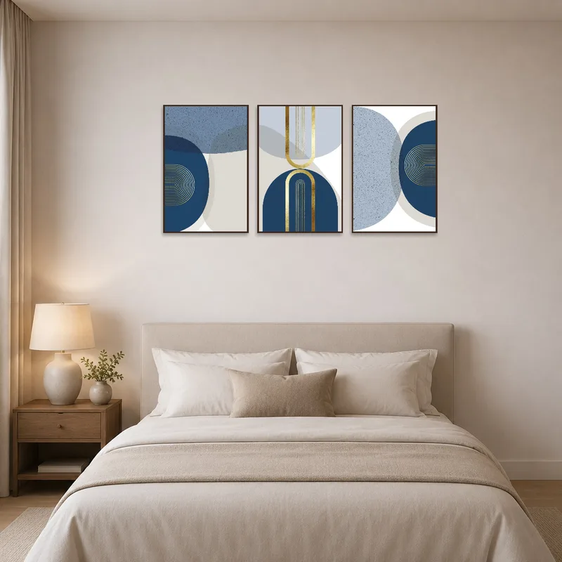 Triptych set with blue and gold designs hangs above a bed with plush bedding.