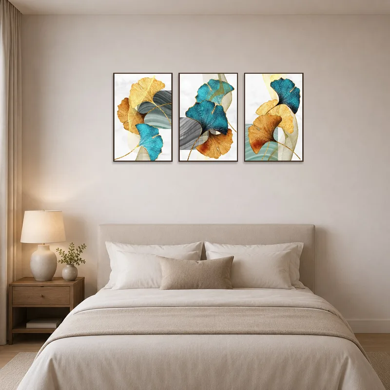 Teal and gold leaf art set above a bed in a softly lit, serene bedroom space.