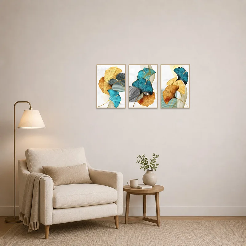 Artistic ginkgo leaf triptych in teal and gold in a cozy reading corner with an armchair.