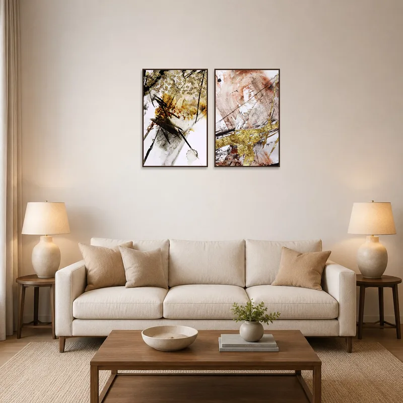 Set of two golden abstract artworks above a modern couch in a living room.