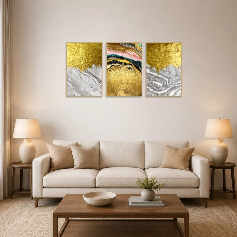Abstract triptych with gold and marble accents on a living room wall above a modern sofa.