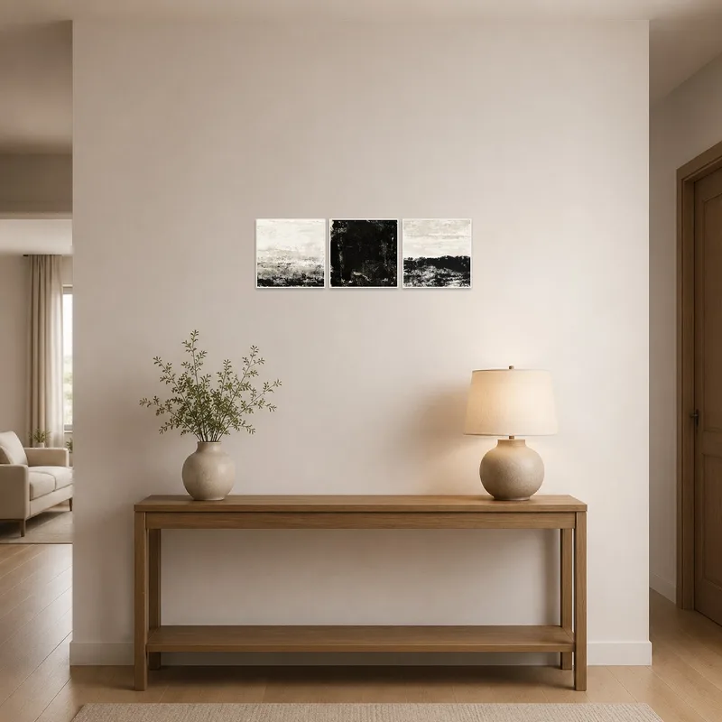 Monochrome abstract triptych with textured layers displayed in an entrance hall.