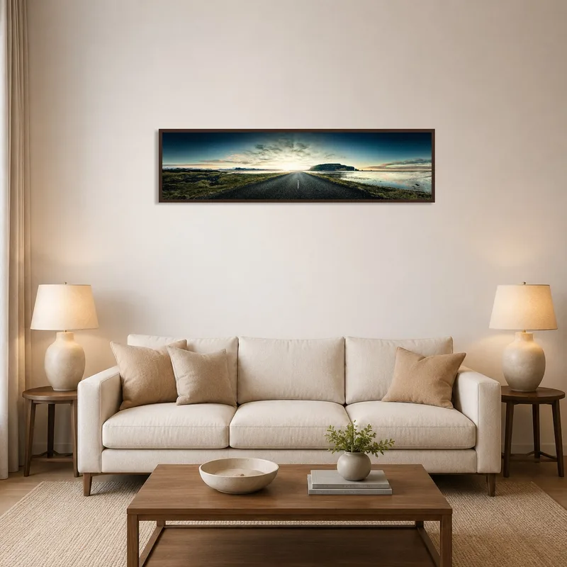 A wide art print of a scenic road leading to the horizon displayed over the living room sofa.