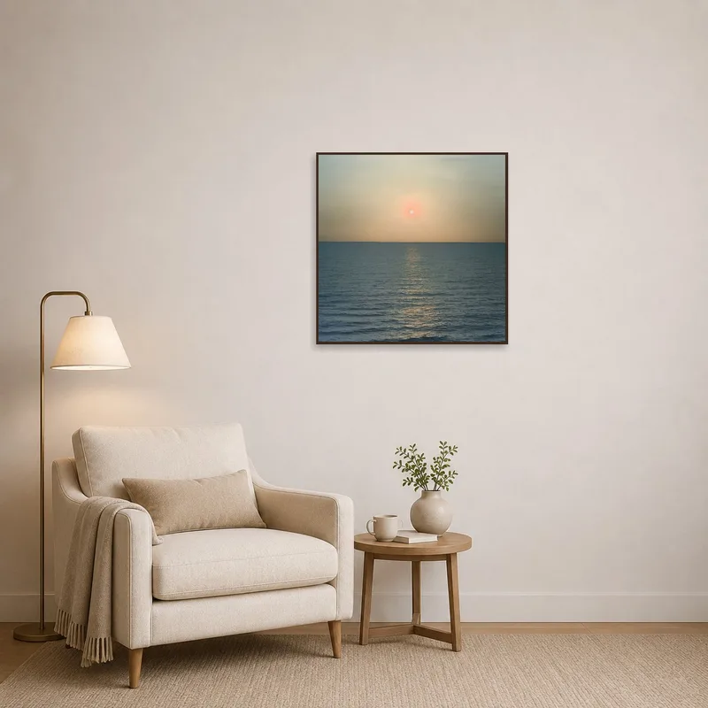 Reading corner with sunset art print over comfy armchair.