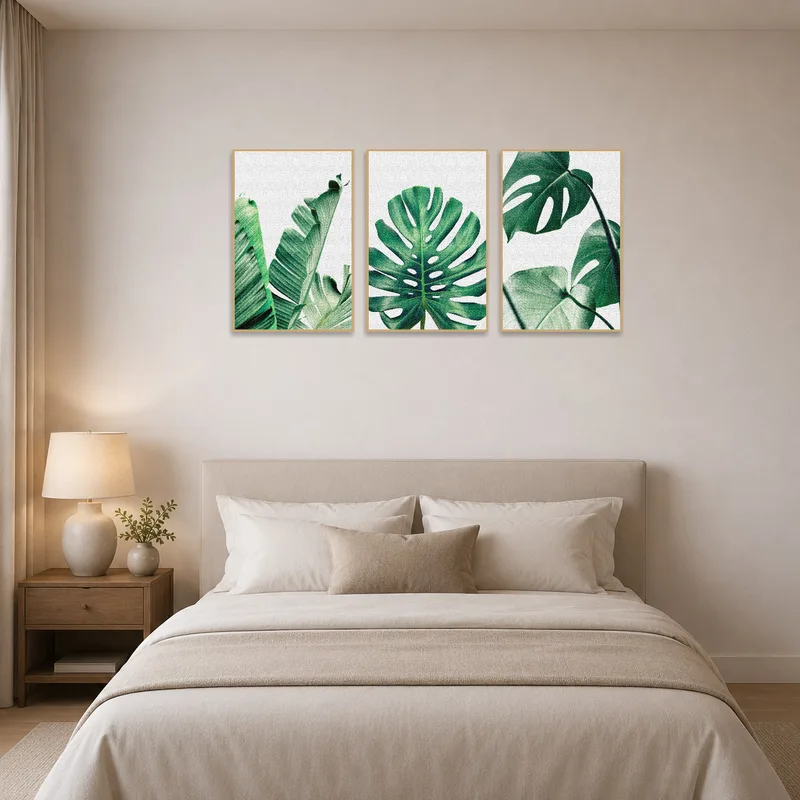 Calming tropical green leaf triptych art above a bed in a serene bedroom setting.